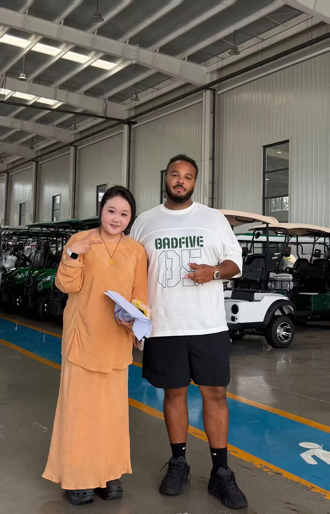 Two people standing beside electric vehicles inside the XINYI factory